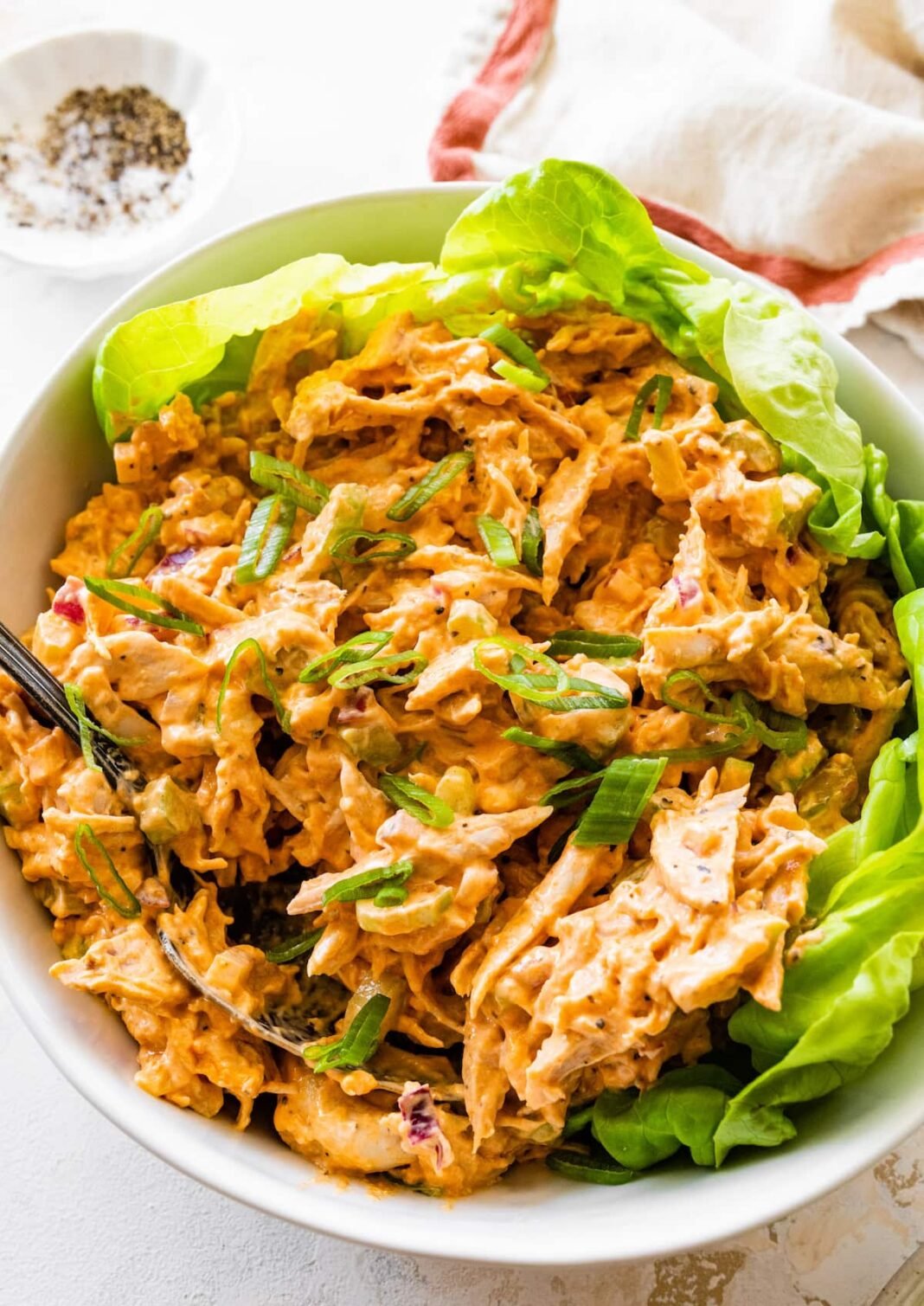 A bowl with buffalo chicken salad on a bed of lettuce.