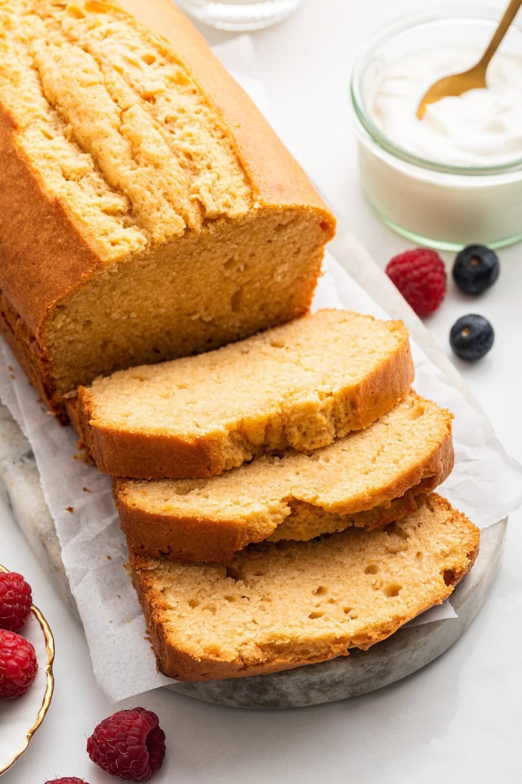 A french yogurt cake loaf with three slices leaning on one another near the loaf.