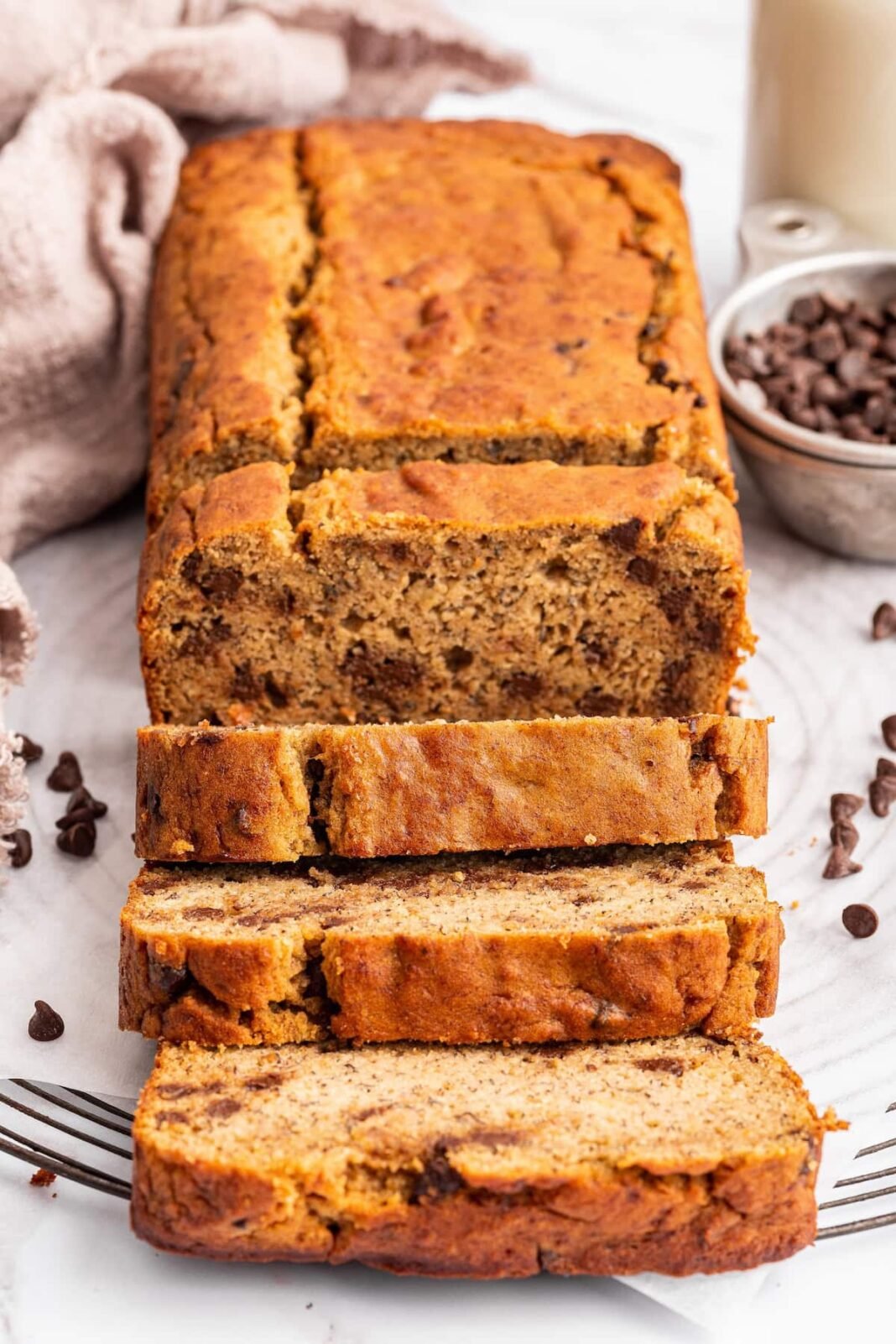 Multiple slices of coconut flour banana bread lean against one another near the loaf of bread.