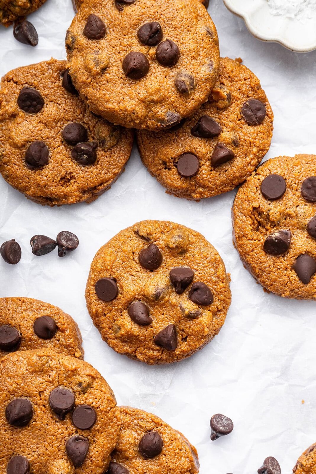 9 flourless peanut butter cookies with chocolate chips spread out on parchment paper.